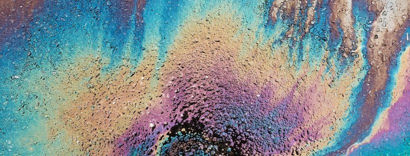 photo of black sneakered feet standing on rainbow oil spill