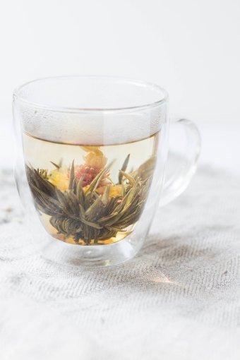 Photo of a clear tea cup with a blooming flower tea