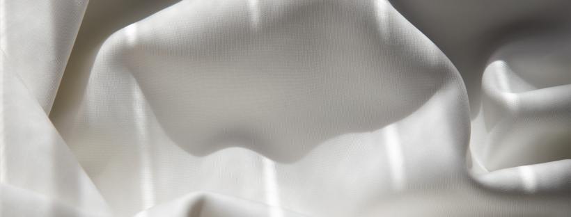 Rumpled white bedsheet splashed with lines of light