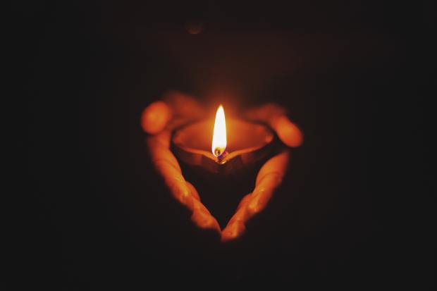 Photo of obscured hands holding a candle