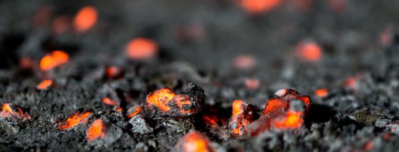 Photo of black and red burning ground and ash.