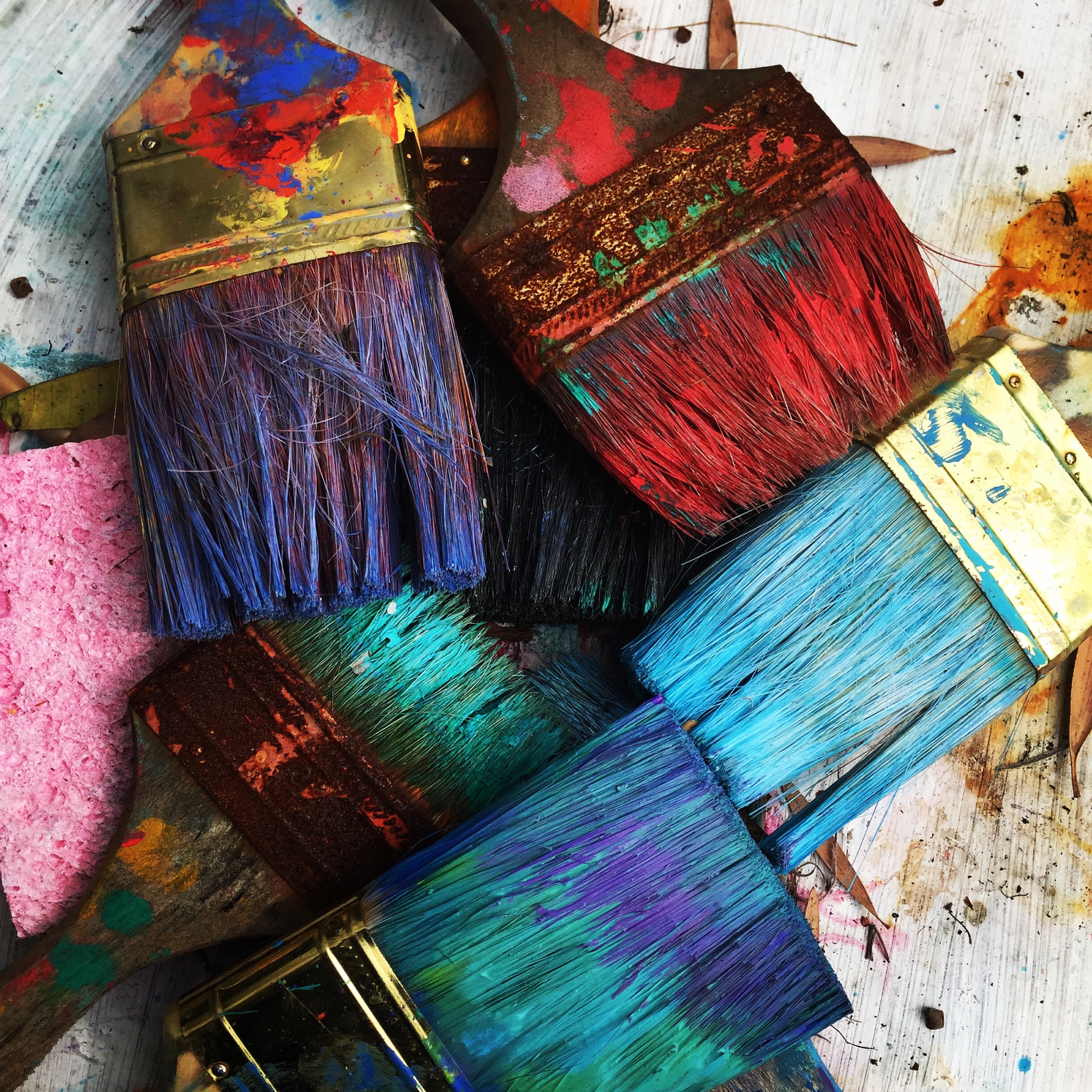 Photo of multiple paint brushes with many different colours of paint
