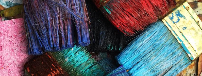 Photo of multiple paint brushes with many different colours of paint