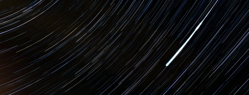 A dark image showing circular streaks of light against a black background, resembling long-exposure star trails.
