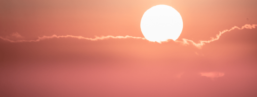 Photo of a pink sunset peeking over clouds.